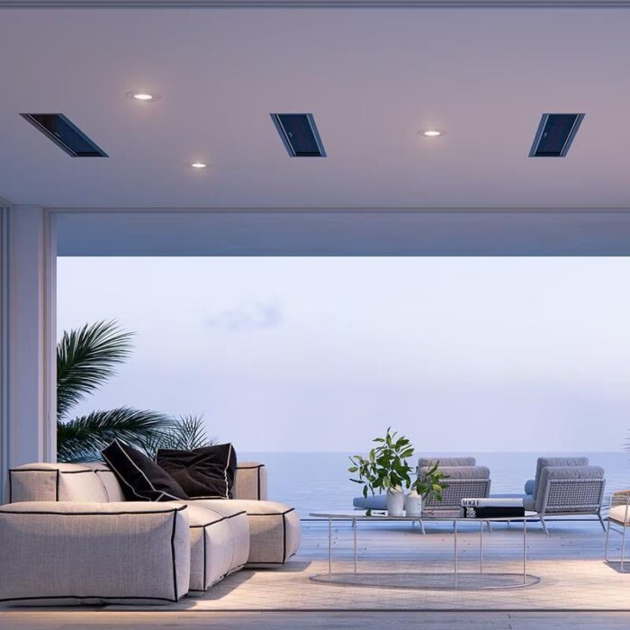 Modern coastal living room with stylish furniture, sea view, and indoor plants, featuring recessed lighting and a glass coffee table.