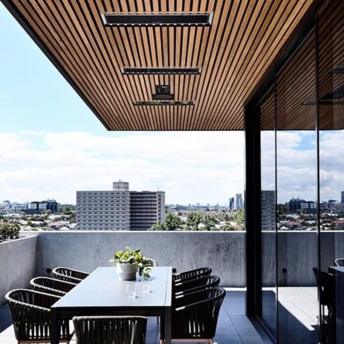 Modern outdoor dining area with a wooden ceiling, glass railing, and city skyline view. Features a sleek table and black wicker chairs, perfect for entertaining.