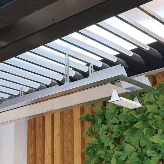 Modern patio cover featuring adjustable louvered roof, sleek metal frame, and integrated lighting, complemented by lush green foliage and wooden wall accents.