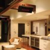Modern kitchen interior with stylish wicker chairs, sleek countertops, and ambient lighting. Features include a stainless steel range hood, a spacious island, and large windows, creating an inviting atmosphere.