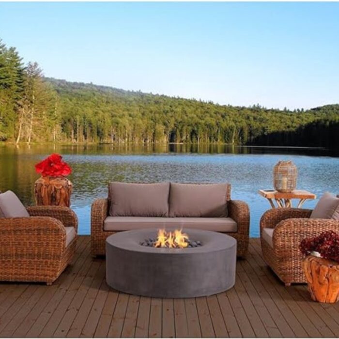 Cozy outdoor seating area with wicker furniture around a modern fire pit, overlooking a serene lake and forest landscape.