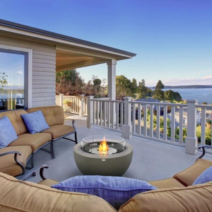 Cozy outdoor seating area with a modern fire pit overlooking a scenic waterfront view.
