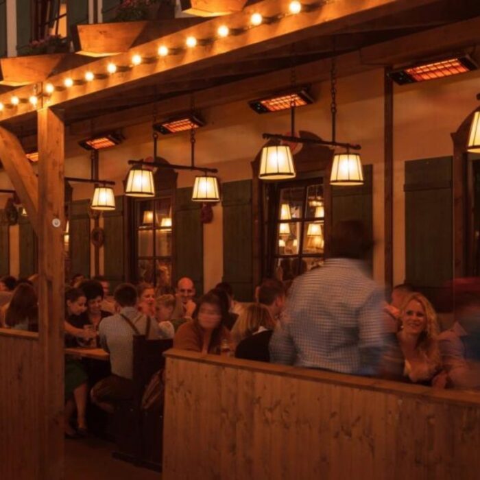 Cozy restaurant interior with wooden decor, warm lighting, and patrons enjoying their meals at communal tables.