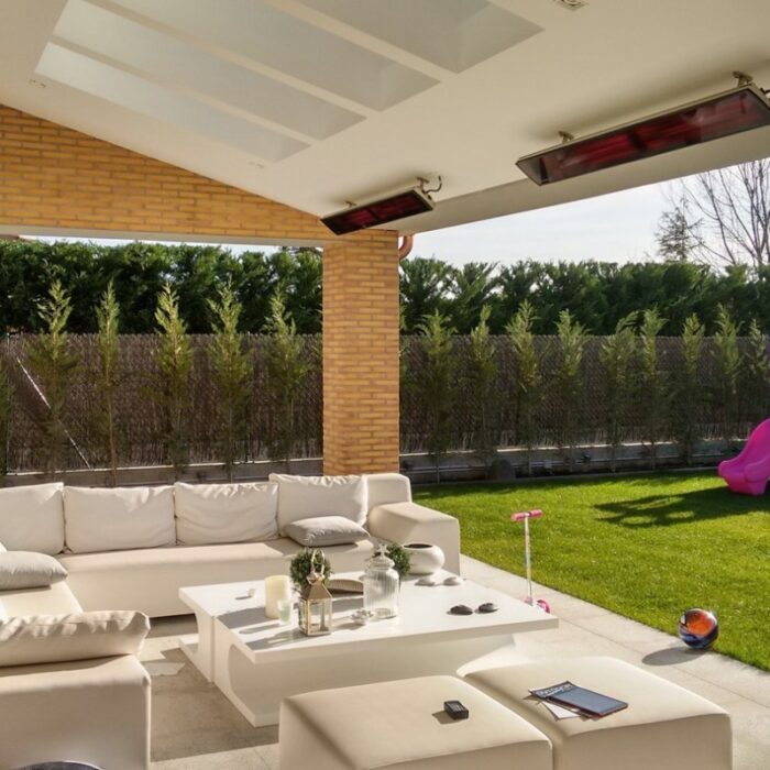 Modern outdoor living space featuring a white sectional sofa, minimalist coffee table, and lush green lawn, complemented by decorative accessories and a playful pink slide in the background.