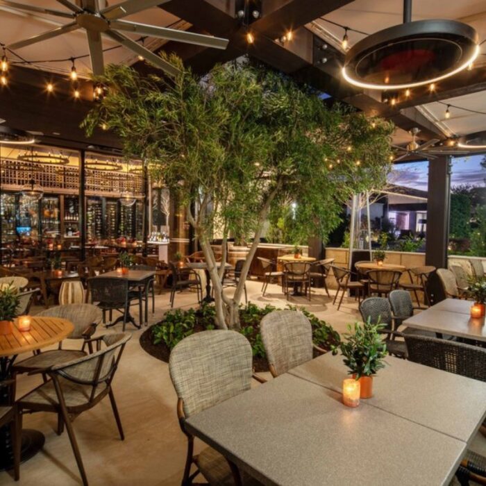 Outdoor dining area featuring stylish tables, ambient lighting, and lush greenery, perfect for a relaxing meal or gathering.
