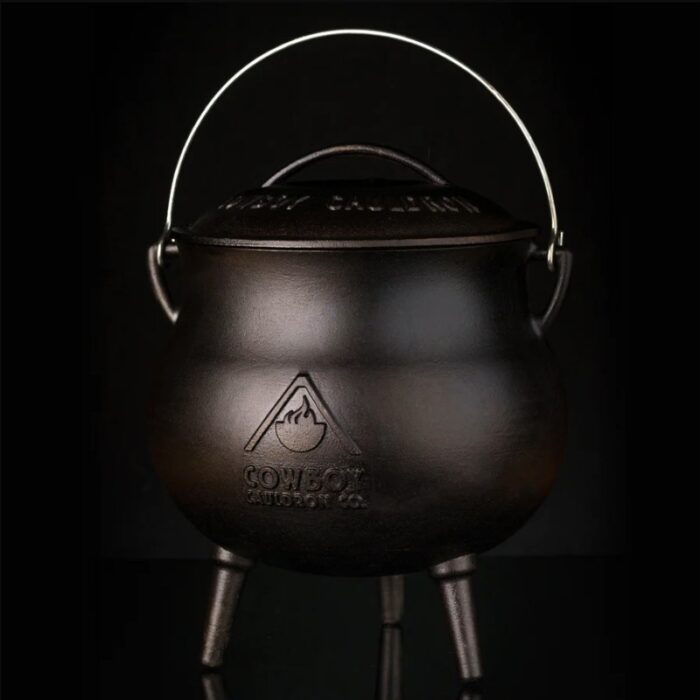 Cast iron cooking pot with a lid and handle, featuring the Cowboy Cooking Co. logo, designed for outdoor cooking.