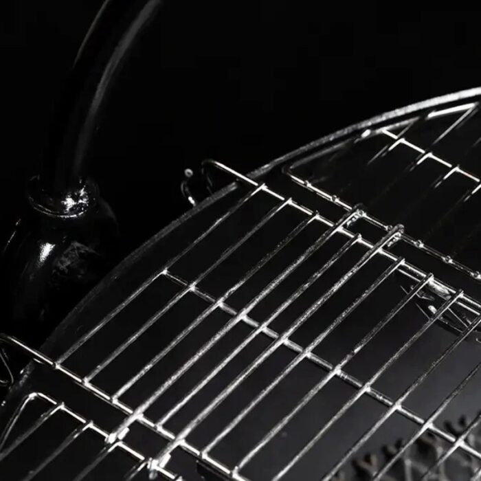 Close-up of a black charcoal grill's chrome cooking grate, showcasing its grid pattern and metallic finish against a dark background.