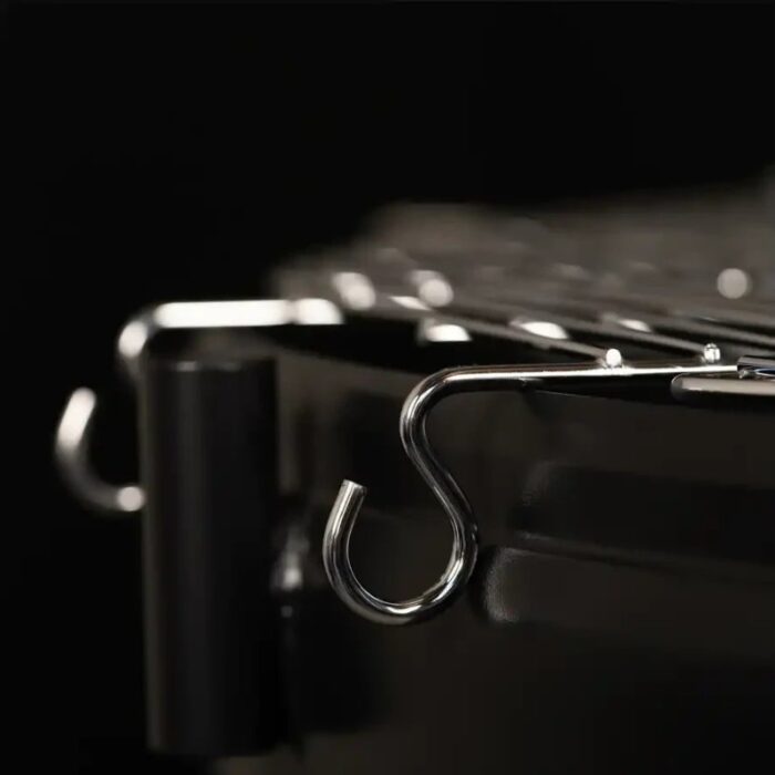 Close-up of metal hooks attached to a grill grate against a dark background.