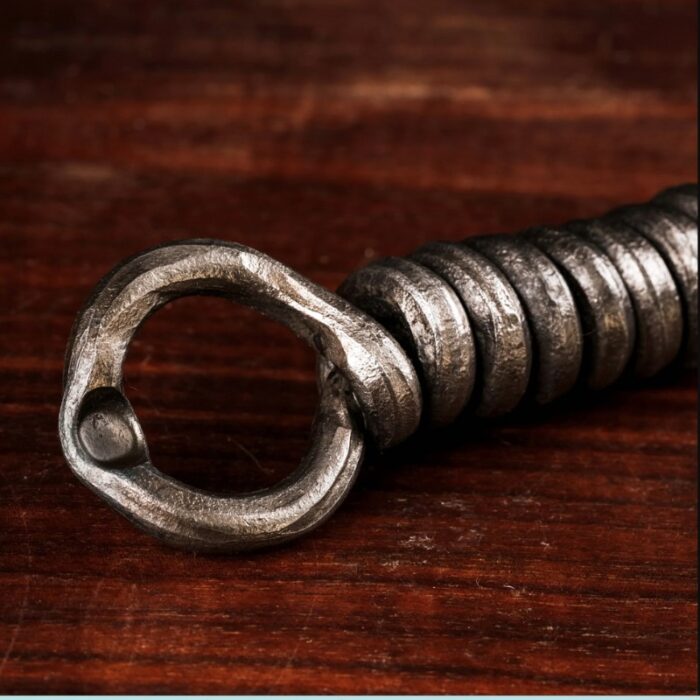 Close-up of a metallic spiraled hook on a wooden surface, showcasing its textured finish and industrial design.