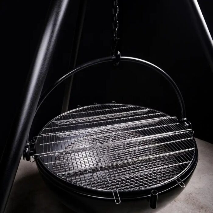 Hanging circular grill with a metallic grate and support chain, designed for outdoor cooking.