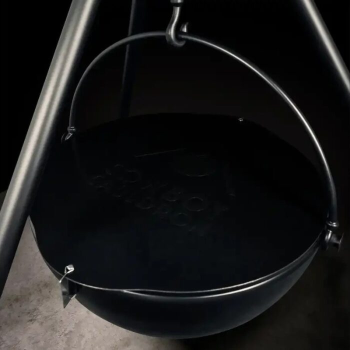 Black cast iron cooking pot suspended from a metal tripod stand, featuring a smooth surface and visible branding.