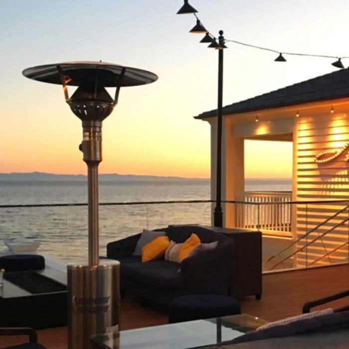 Outdoor patio with a gas heater, cozy seating, and a sunset view over the ocean.