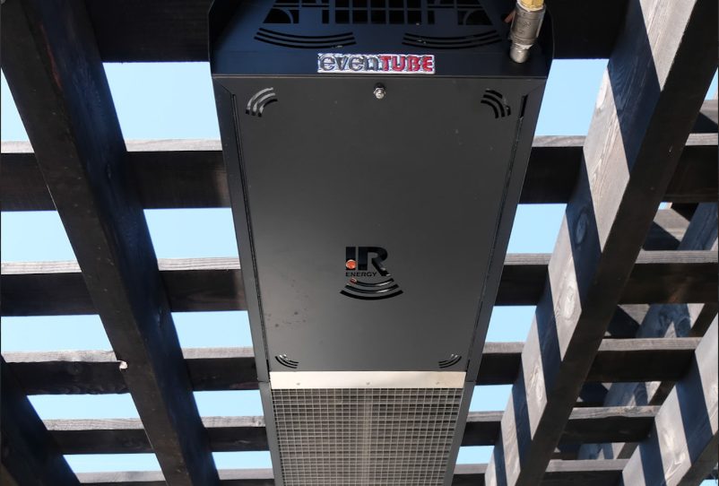 Close-up of a black IR Energy evenTUBE heater mounted between dark pergola rafters